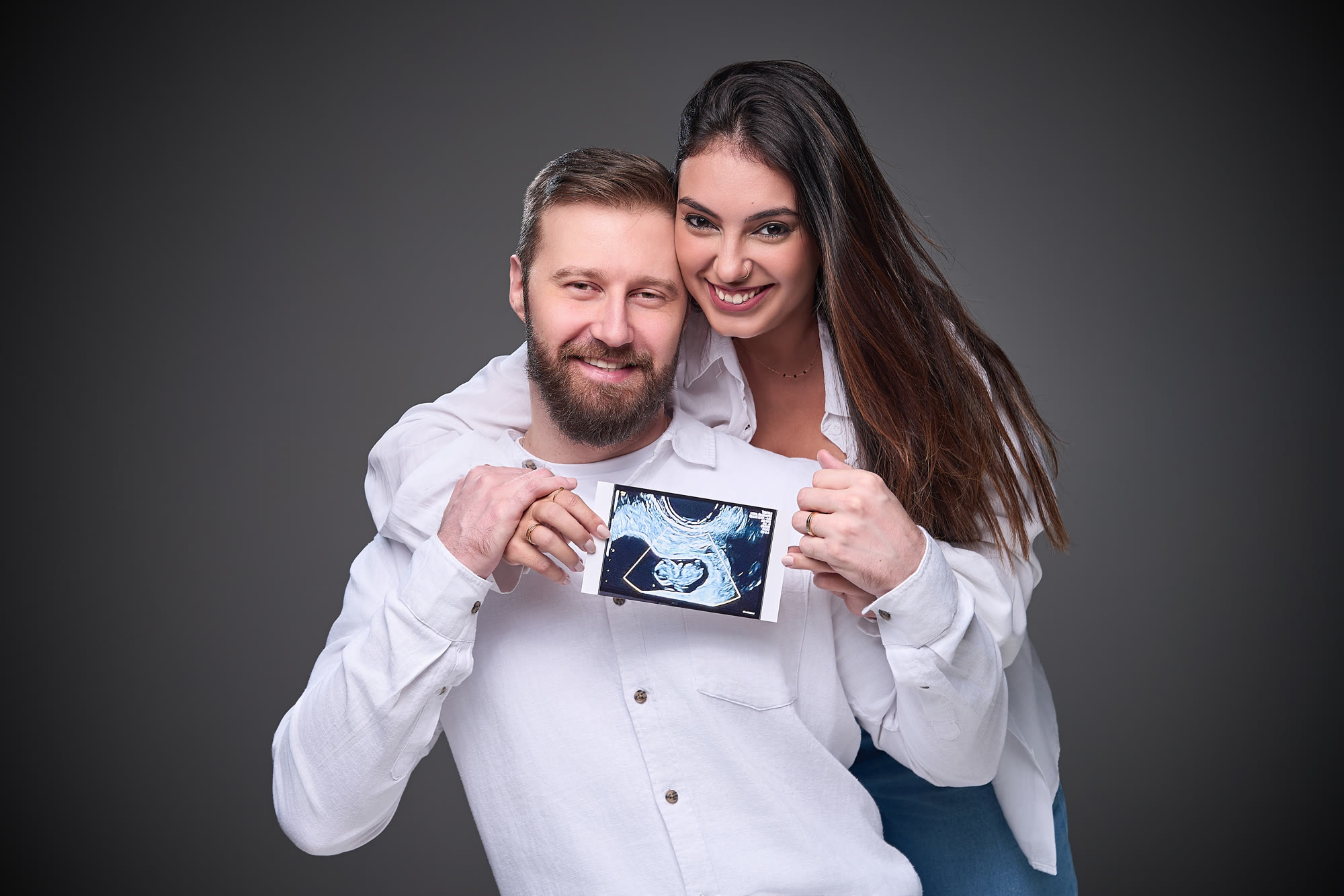 Casal observa uma imagem de ultrassom durante o ensaio gestante