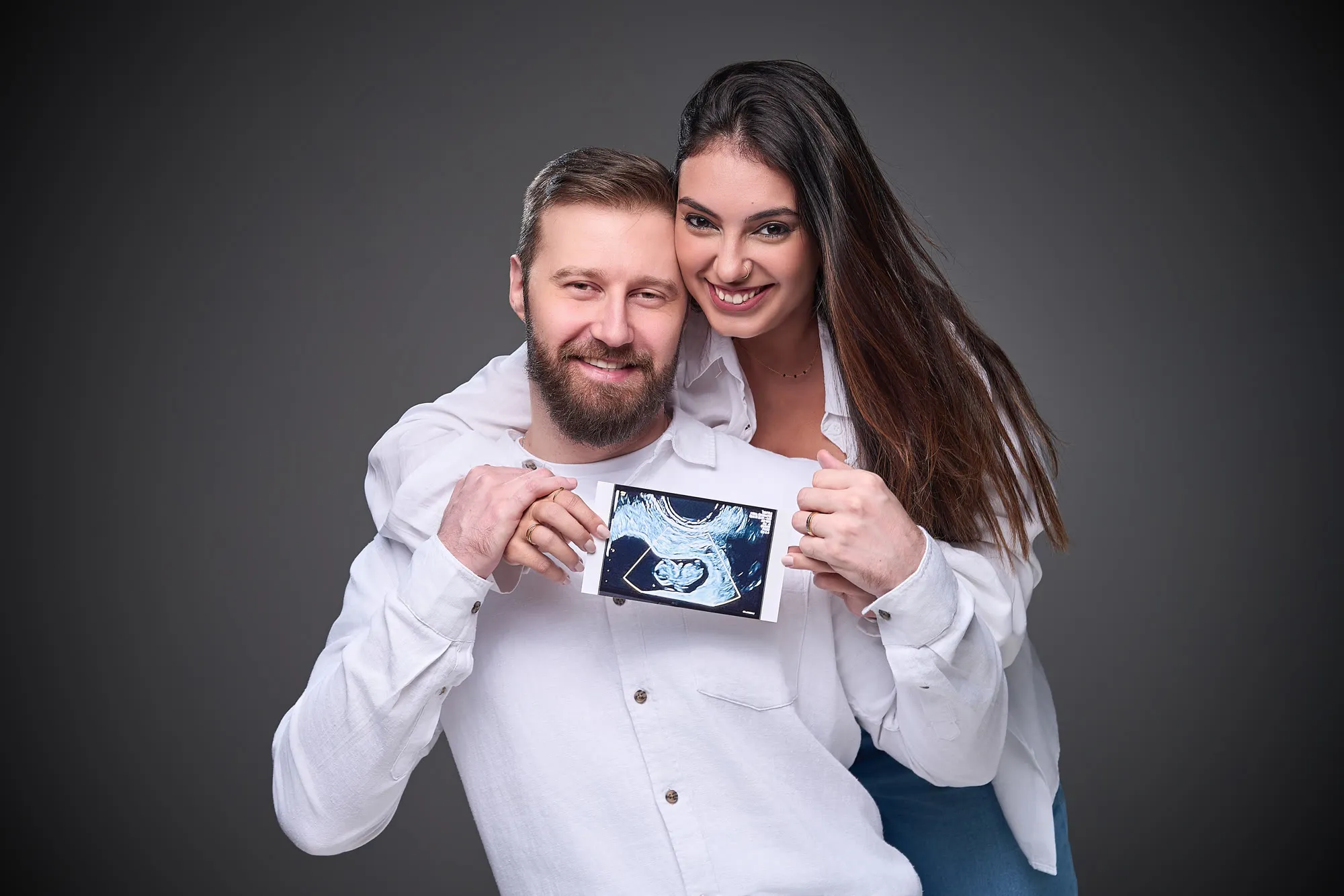 Casal observa uma imagem de ultrassom durante o ensaio gestante