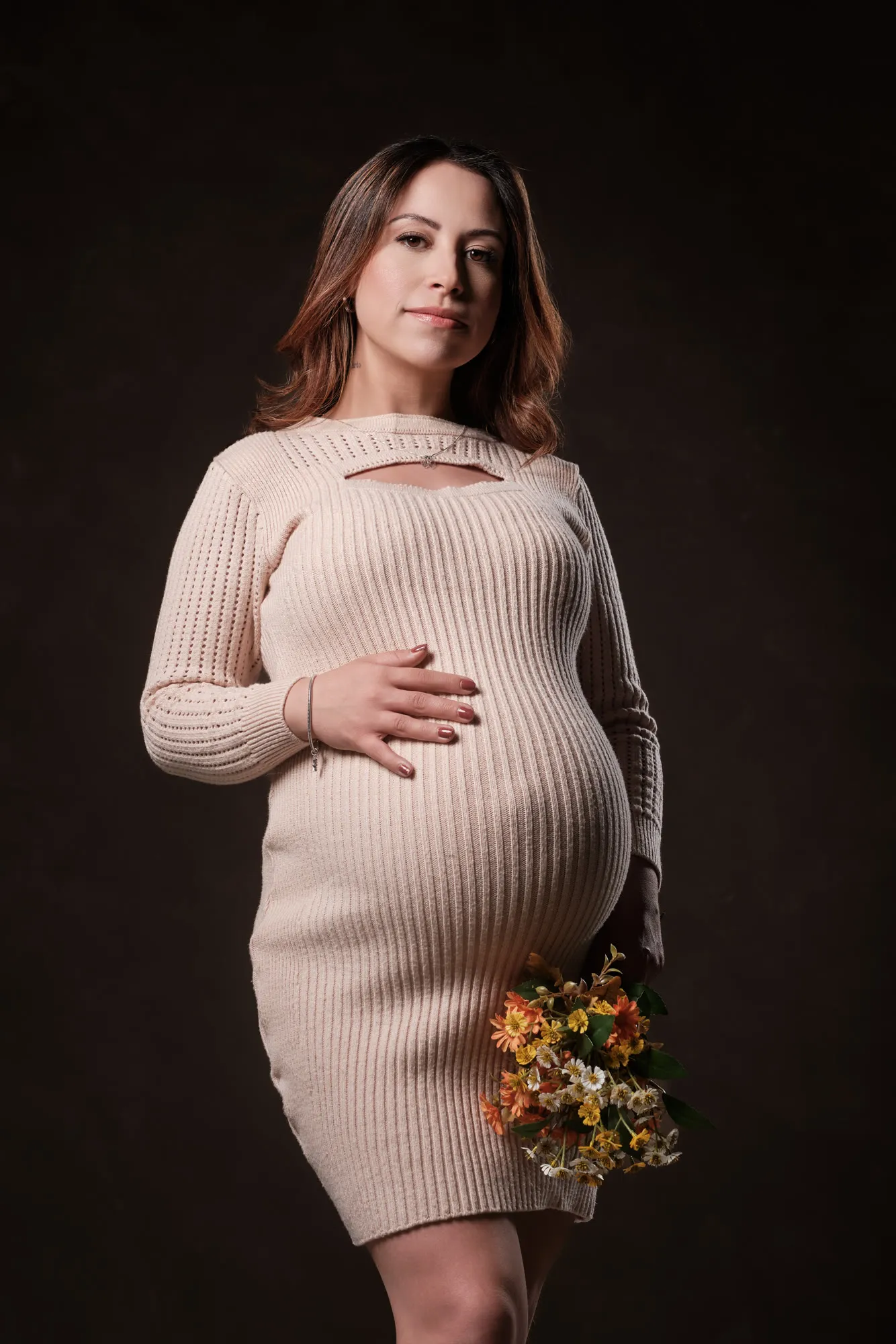 Gestante com vestido claro e flores em fundo escuro